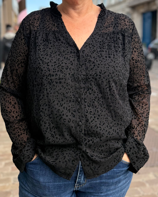 Chemise noire texturée à motifs et col V portée avec un jean